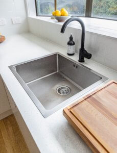 A stainless steel kitchen sink paired with black fixutres.